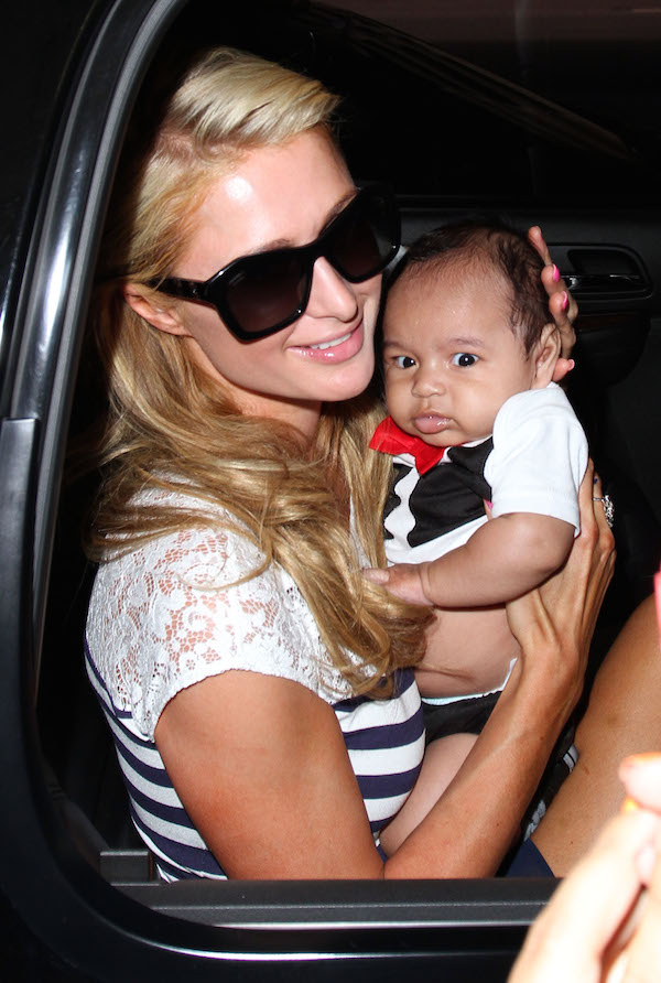 Dlisted | Paris Hilton poses with a baby while arriving at LAX from Korea